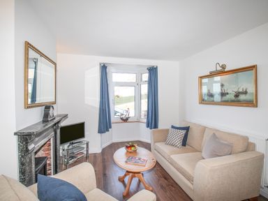 A living room with beige sofas a wooden coffee table a television and a painting at The Shambles in Fortuneswell