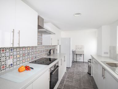 A kitchen with white cabinets and patterned backsplash at The Shambles in Fortuneswell