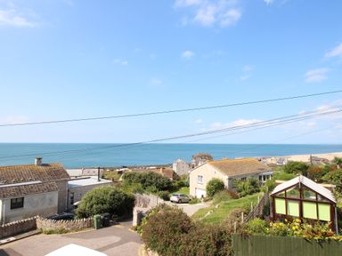 A coastal view with houses gardens cars and power lines overlooking the sea at The Shambles in Fortuneswell
