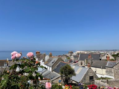 A coastal village with stone houses and pink flowers in the foreground by the sea at The Shambles in Fortuneswell