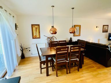 A dining room with a wooden table and six chairs and two pendant lights over it at Yr Encil in Llanddaniel near Gaerwen