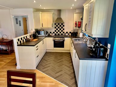 A kitchen with white cabinets black countertops and checkered backsplash at Yr Encil in Llanddaniel near Gaerwen