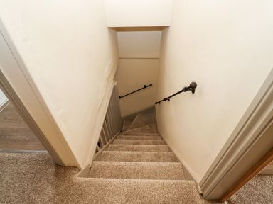 A carpeted staircase with handrails on both sides leading down at 4 Lower Folley in Chipping Campden