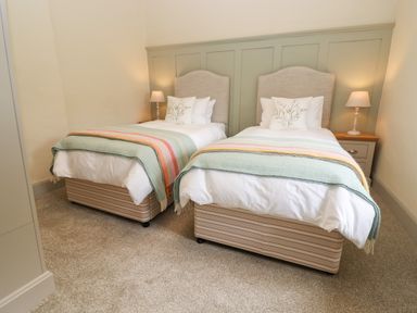 A bedroom with two single beds with green headboards and bedside tables with lamps at 4 Lower Folley in Chipping Campden