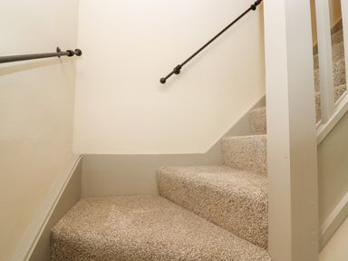A staircase with beige carpet and black handrails at 4 Lower Folley in Chipping Campden