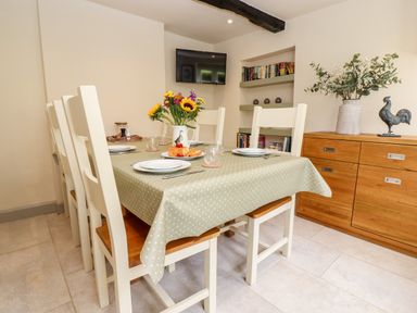A dining room with a table set for four and flowers on the table at 4 Lower Folley in Chipping Campden