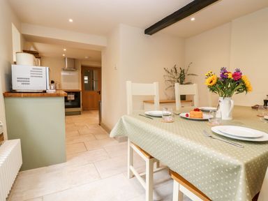 A kitchen and dining area with a table set with plates and a vase of flowers at 4 Lower Folley in Chipping Campden