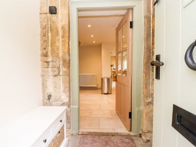 An open wooden door showing a hallway with a radiator and a trash bin at 4 Lower Folley in Chipping Campden