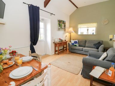 A living room with a dining table set for breakfast and two sofas at Carreg Cennen Cottage in Llandeilo
