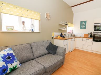 A kitchen with a gray sofa and yellow window blinds at Carreg Cennen Cottage in Llandeilo