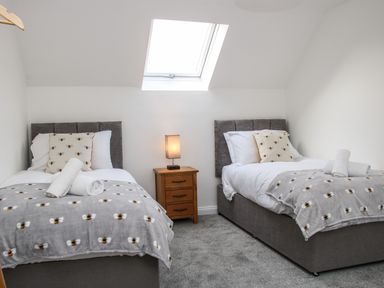 A bedroom with two single beds a nightstand with a lamp and a skylight at The Little Beehive in Abberley