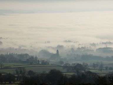 A landscape with fields and trees covered in fog at The Little Beehive in Abberley