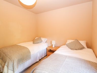 A bedroom with two single beds separated by a wooden nightstand and a lamp at The Firs in Wendling near Dereham