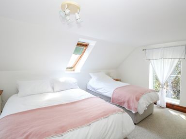 A bedroom with two beds a skylight window and a window with white curtains at The Firs in Wendling near Dereham