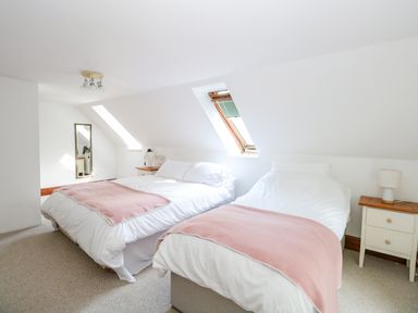 A bedroom with two beds and bedside tables under skylight windows at The Firs in Wendling near Dereham