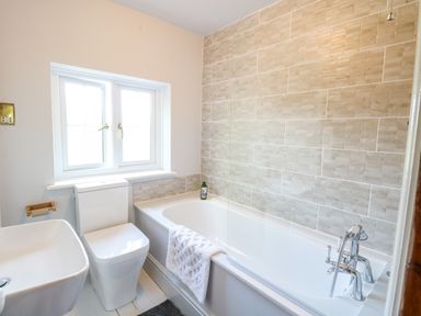 A bathroom with a bathtub a sink a toilet and a window at The Firs in Wendling near Dereham