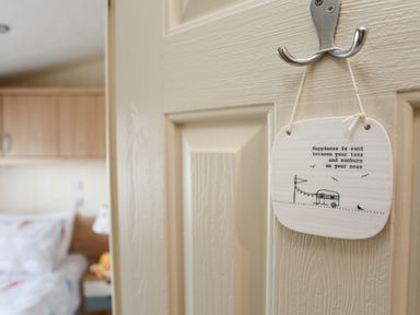 A door with a metal hook holding a hanging plaque with a quote in a bedroom at Tegfryn Bach in Llangoed near Beaumaris
