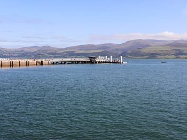 A pier extending into a body of water with hills in the background at Tegfryn Bach in Llangoed near Beaumaris