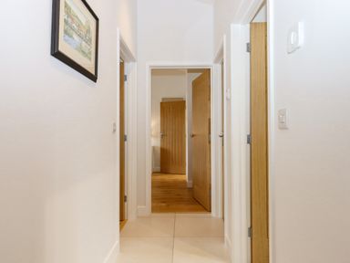 A hallway with white walls wooden doors and a framed picture on the wall at Woodpecker Lodge in Butterleigh