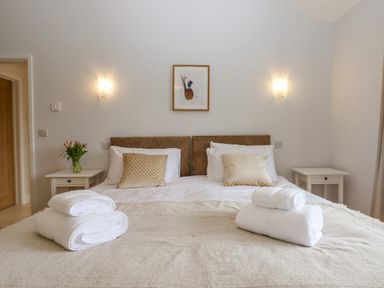 A bedroom with a double bed two bedside tables flowers and framed artwork at Woodpecker Lodge in Butterleigh