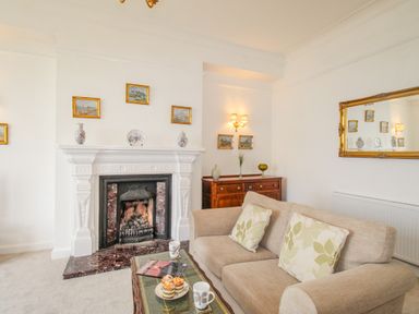 A living room with a fireplace sofa coffee table and wooden cabinet at Weymouth Bay Apartment A Weymouth
