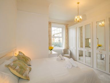 A bedroom with a bed pillows mirrors on wardrobes and a window at Weymouth Bay Apartment A in Weymouth