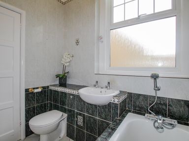 A bathroom with a toilet sink bathtub and a window at Weymouth Bay Apartment A in Weymouth