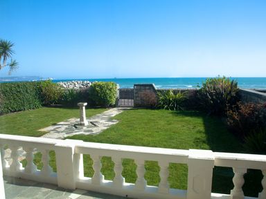 A garden with grass shrubs stone path and a birdbath overlooking the sea at Weymouth Bay Apartment A Weymouth