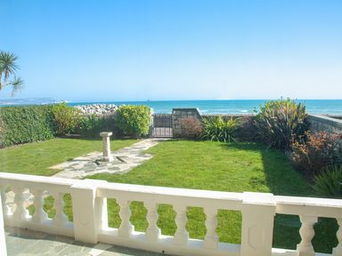 A garden with grass and a stone birdbath overlooking the sea at Weymouth Bay Apartment A in Weymouth