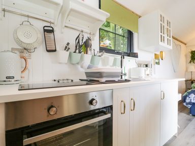 A kitchen counter with a built in oven stovetop utensils kettle toaster and a sink at High Rigg Shepherd's Sunset in Brampton Cumbria