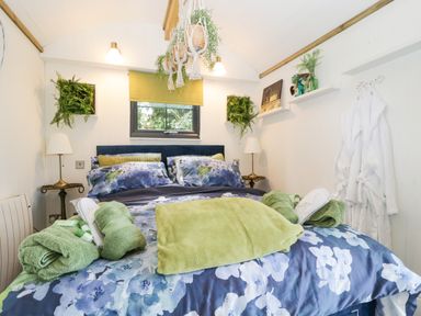A bedroom with a bed covered in floral bedding and green towels at High Rigg Shepherd's Sunset in Brampton Cumbria
