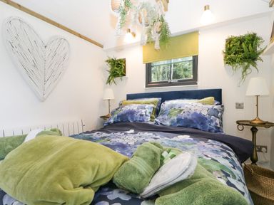 A bedroom with a bed with blue and green floral bedding and green towels at High Rigg Shepherd's Sunset in Brampton Cumbria