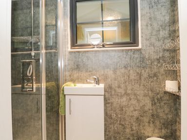 A bathroom with a small white sink cabinet towel and shower enclosure at High Rigg Shepherd's Sunset in Brampton Cumbria