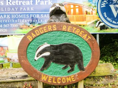 A wooden sign with a badger image and text reading Badgers Retreat Welcome at Badgers Retreat Tunstall near Hipswell