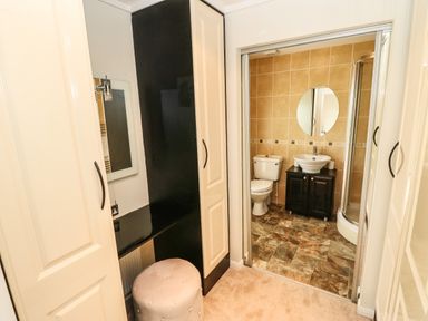 A dressing area with a stool and mirror next to a bathroom with a toilet sink and shower at Badgers Retreat in Tunstall near Hipswell