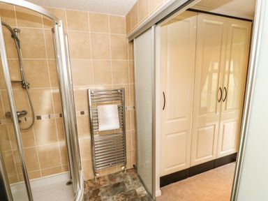 A bathroom with a shower enclosure towel rack and wardrobe with sliding doors at Badgers Retreat in Tunstall near Hipswell