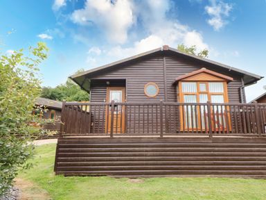 Exterior view of a wooden cabin with porch and railing at Badgers Retreat in Tunstall near Hipswell
