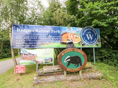 Entrance signs for Badgers Retreat Park holiday park with a wooden badger sculpture and speed limit sign at Badgers Retreat in Tunstall near Hipswell