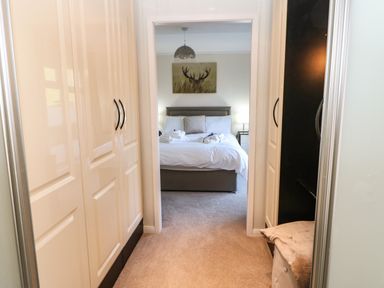 A bedroom with a bed visible through a doorway between two wardrobes at Badgers Retreat in Tunstall near Hipswell