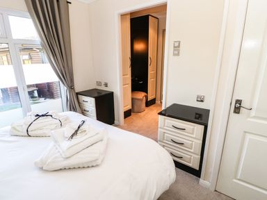 A bedroom with a bed towels on it two bedside cabinets and a dressing area at Badgers Retreat in Tunstall near Hipswell
