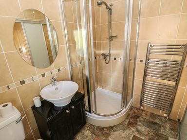 A bathroom with a shower enclosure a sink with cabinet a heated towel rail and a toilet at Badgers Retreat in Tunstall near Hipswell