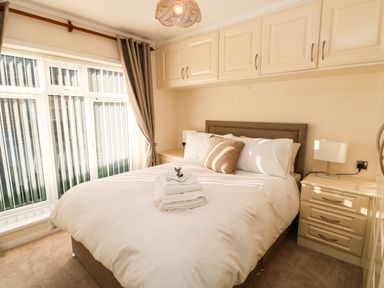 A bedroom with a bed white linens bedside tables and overhead cabinets at Badgers Retreat in Tunstall near Hipswell