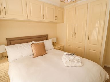 A bedroom with a made bed towels on it bedside tables and built in wardrobes at Badgers Retreat in Tunstall near Hipswell