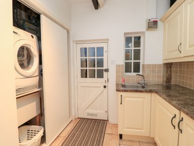 A laundry room with a washing machine and sink at Butlers Cottage in Burford