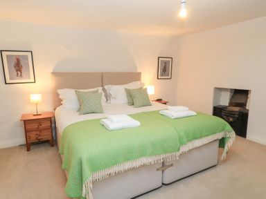 A bedroom with a bed and bedside lamp at Butlers Cottage Burford