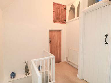 A hallway with a staircase and a rabbit statue at Butlers Cottage Burford