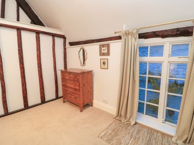 A bedroom with a chest of drawers and a window at Butlers Cottage, Burford