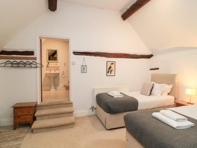 A bedroom with two beds and stairs at Butlers Cottage Burford