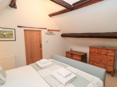 A bedroom with a bed and wooden furniture at Butlers Cottage in Burford