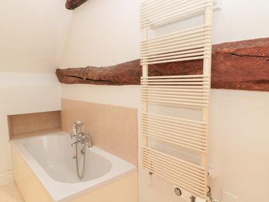 A bathroom with a bathtub and towel radiator at Butlers Cottage in Burford